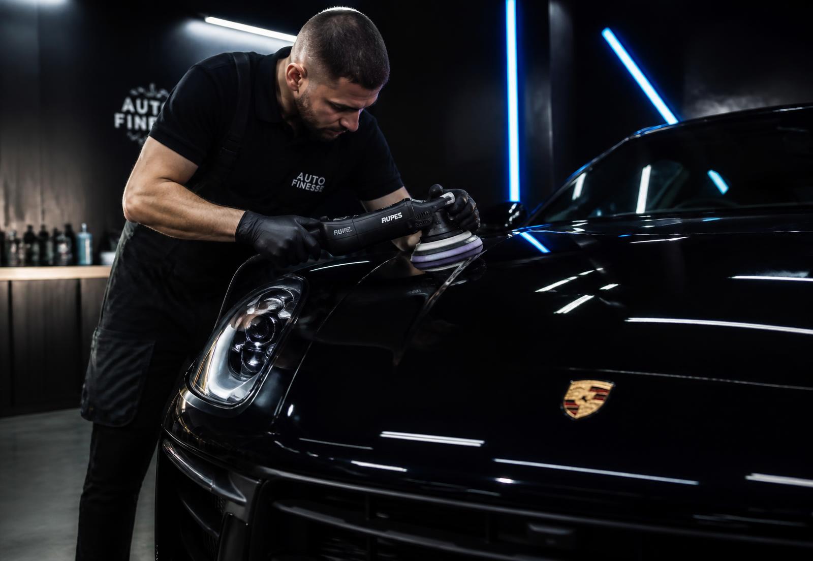 Detailer profesional puliendo la pintura de un auto premium en un taller